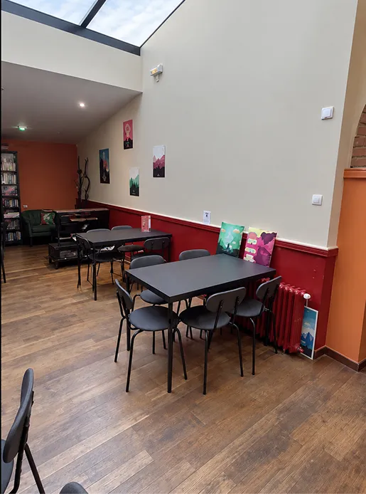 La salle sous verrière du Repaire du Phoenix, tables et chaises sur parquet